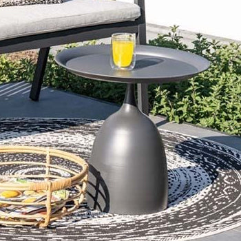 Outdoor patio setting with a bench, table, and decorative items on a stone patio.