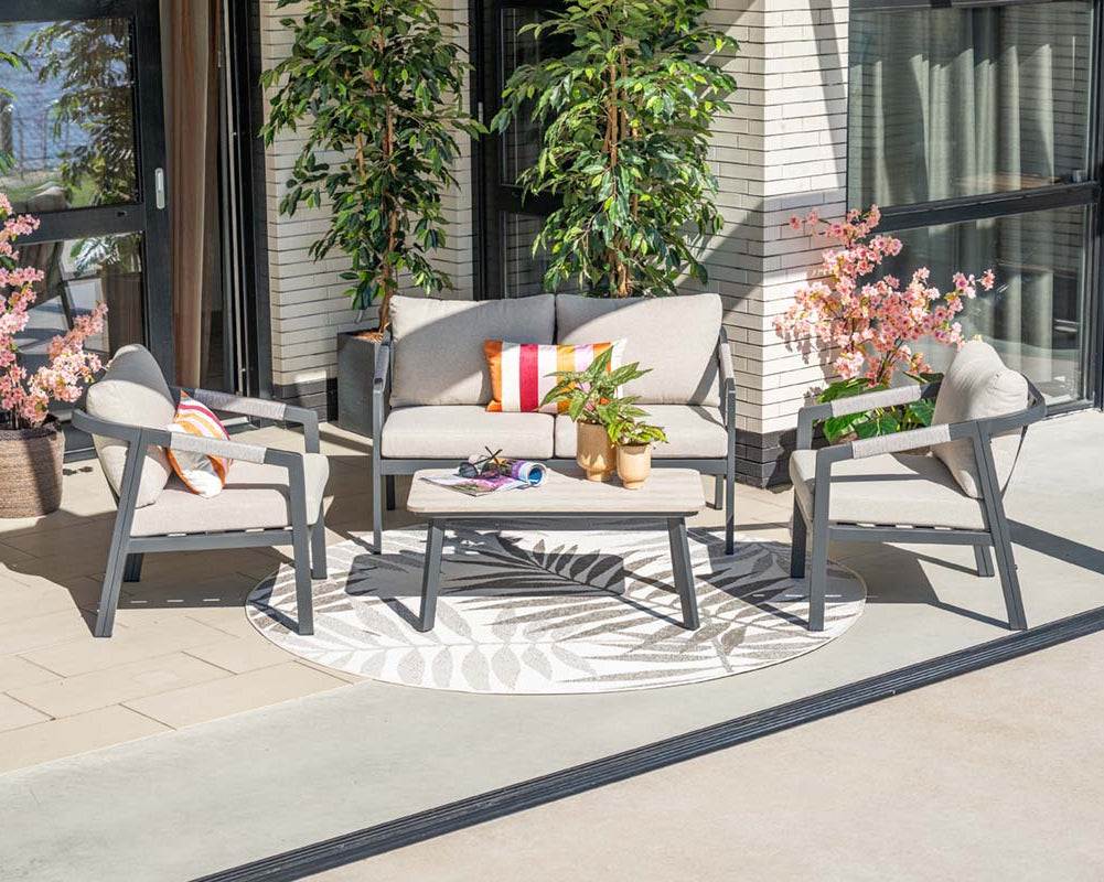 Outdoor patio set with cushions and a small table on a patio area.