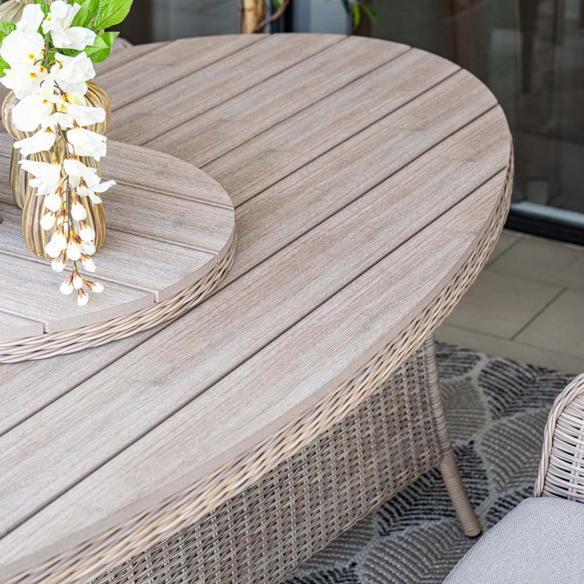 Wooden outdoor table with a vase of white flowers on a patio setting