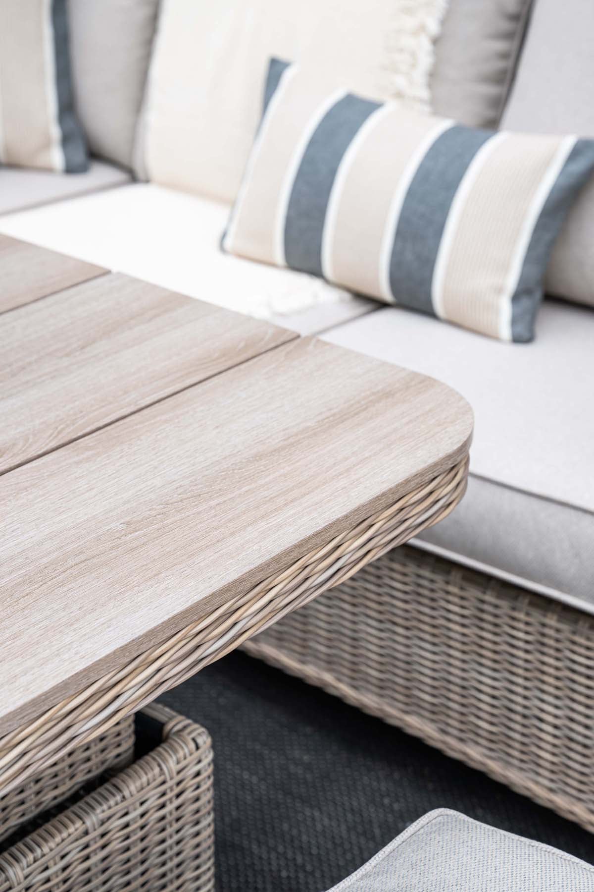Outdoor furniture set with a wooden table and striped cushions on a sofa.