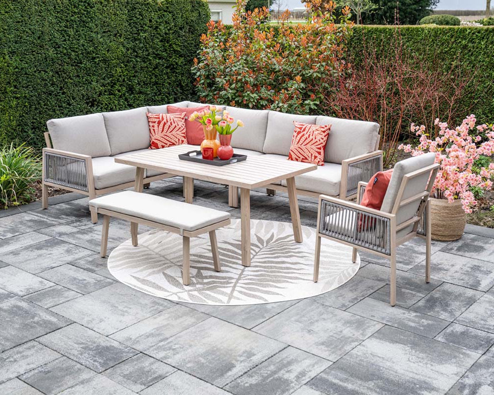 Outdoor patio set with a sofa, table, and chairs on a stone patio.