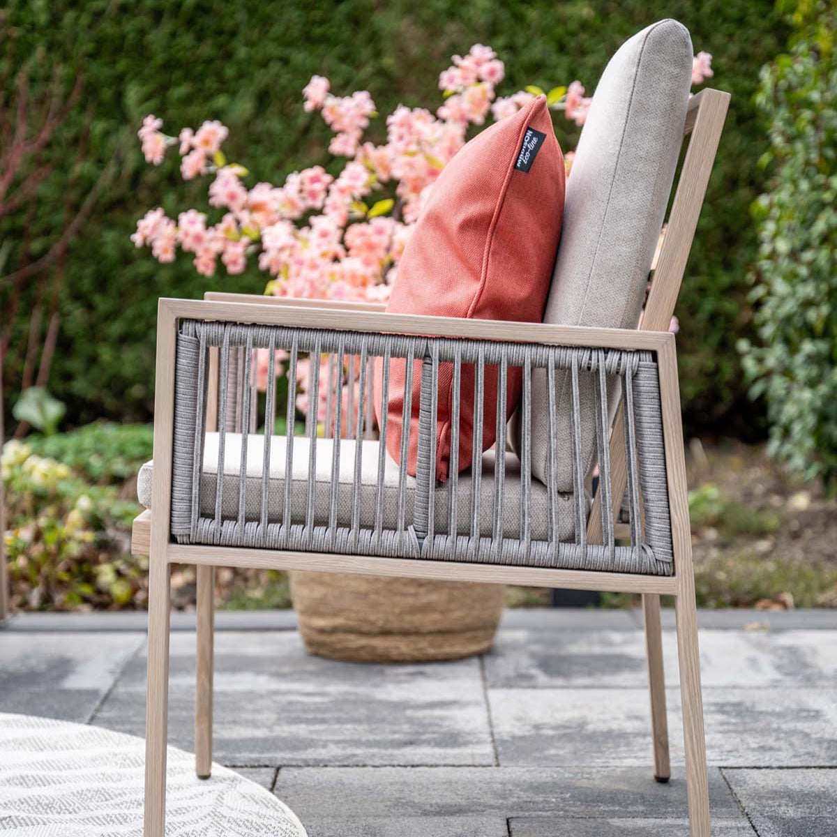 Outdoor chair with cushions on a patio area with flowers in the background