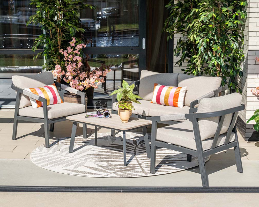 Outdoor patio set with gray chairs, a coffee table, and colorful cushions on a patio.