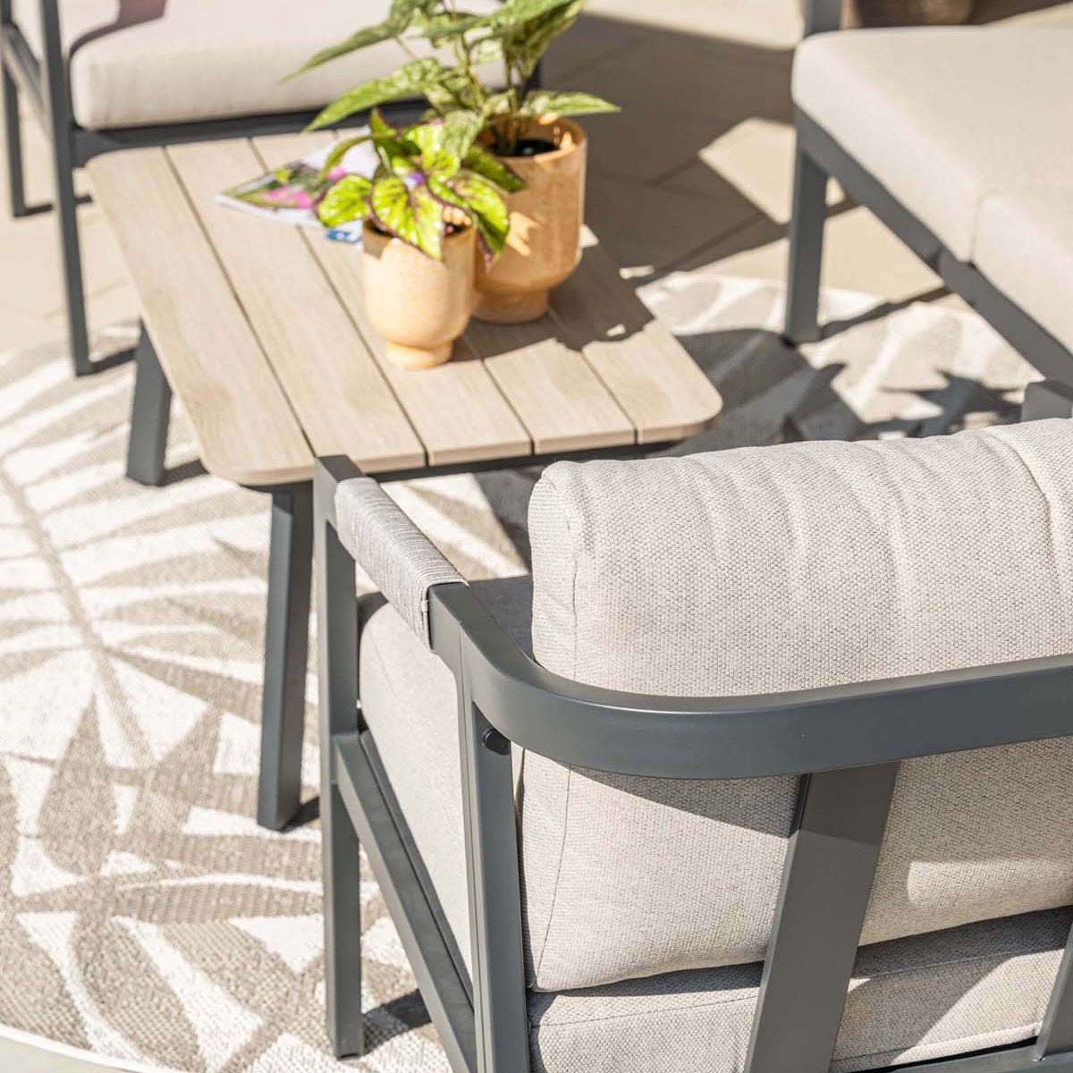 Outdoor furniture set with chairs, table, and potted plants on a patio.