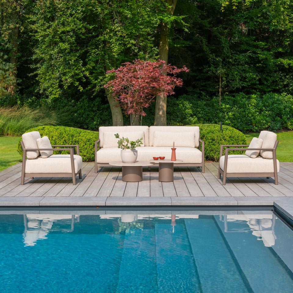 Outdoor patio set with beige cushions by a poolside