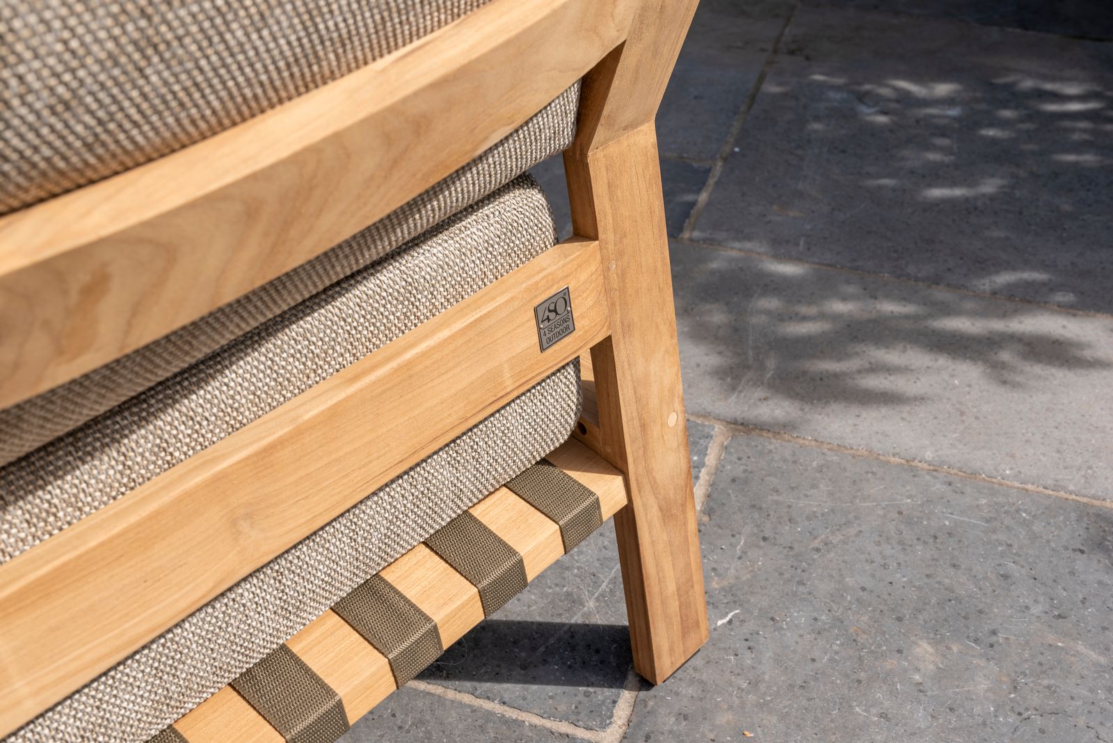 Wooden chair with gray cushion on a stone pavement