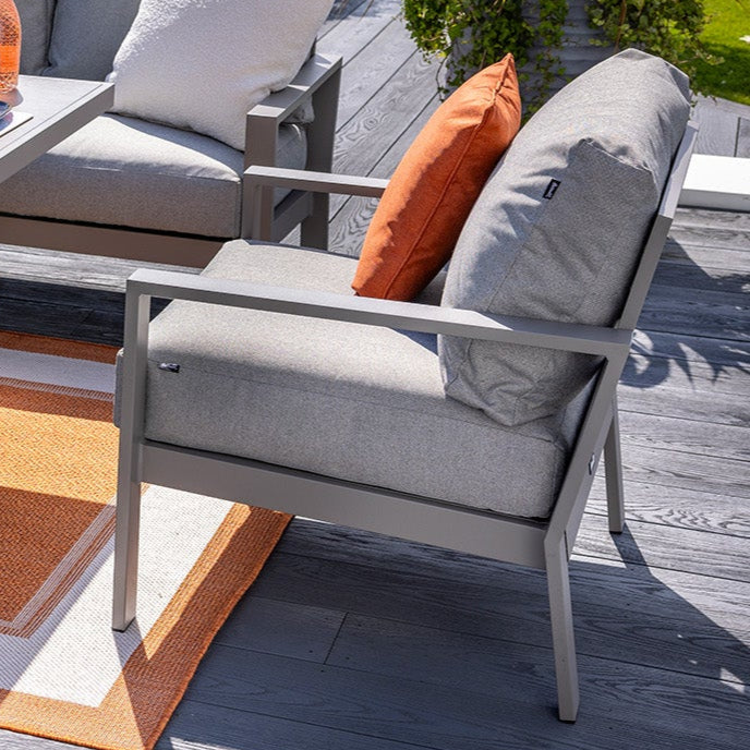 Outdoor patio set with gray cushions and orange pillows on a wooden deck.