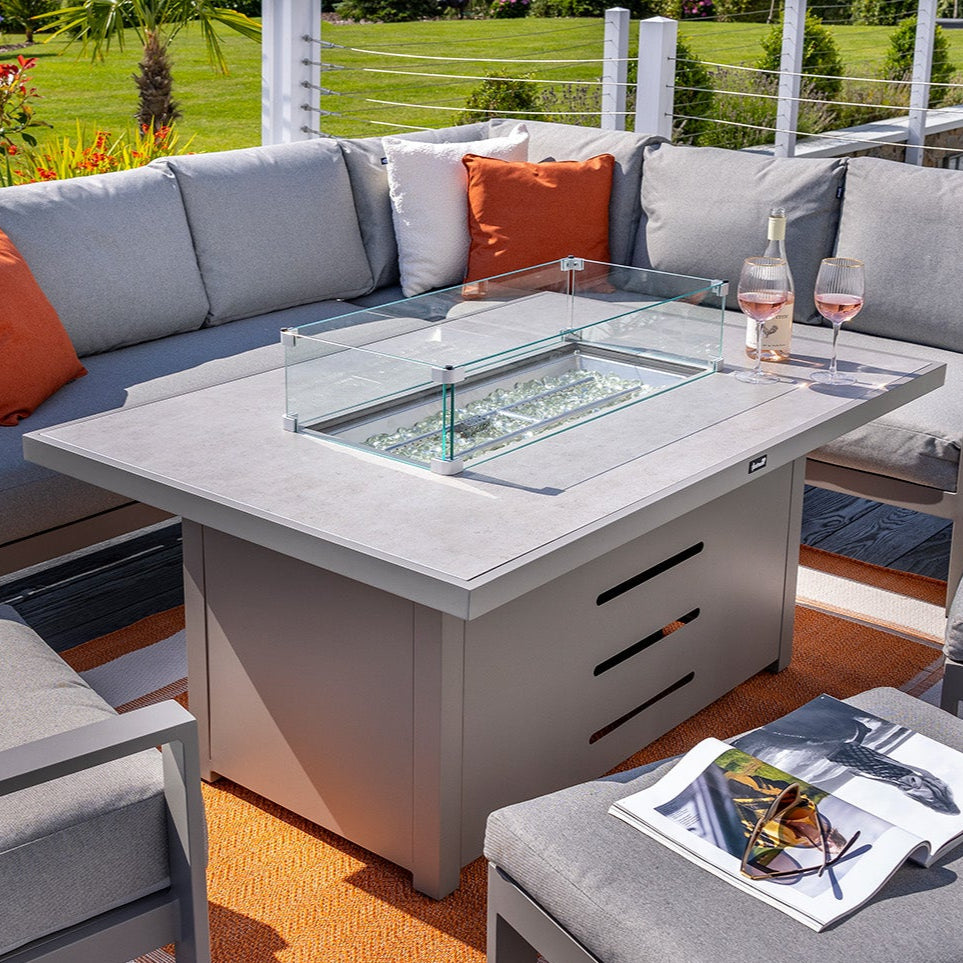 Outdoor patio set with sectional sofa, fire pit table, and chairs on a deck.