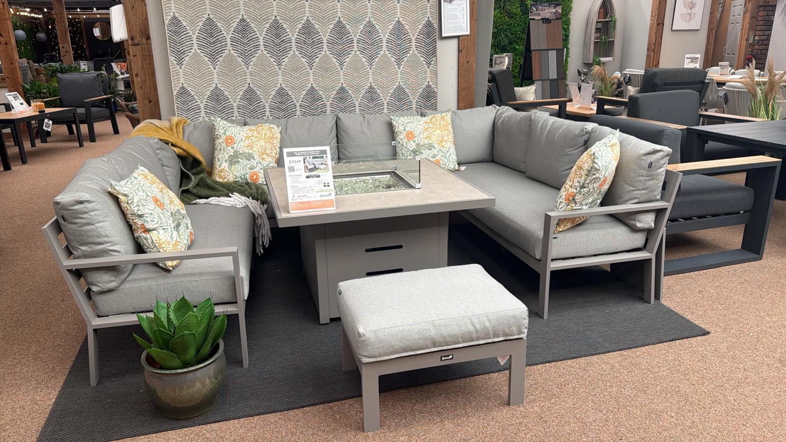 Outdoor furniture set with gray sofas, ottoman, and table in a showroom setting.