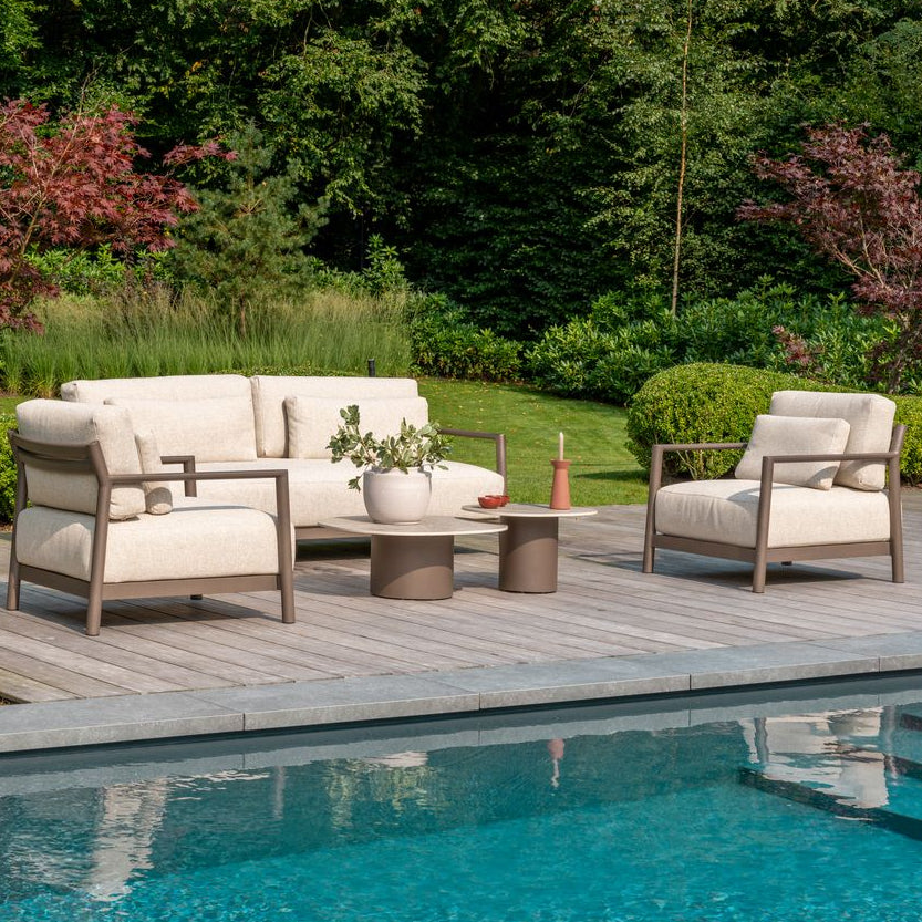 Outdoor patio with white furniture by a poolside in a garden setting